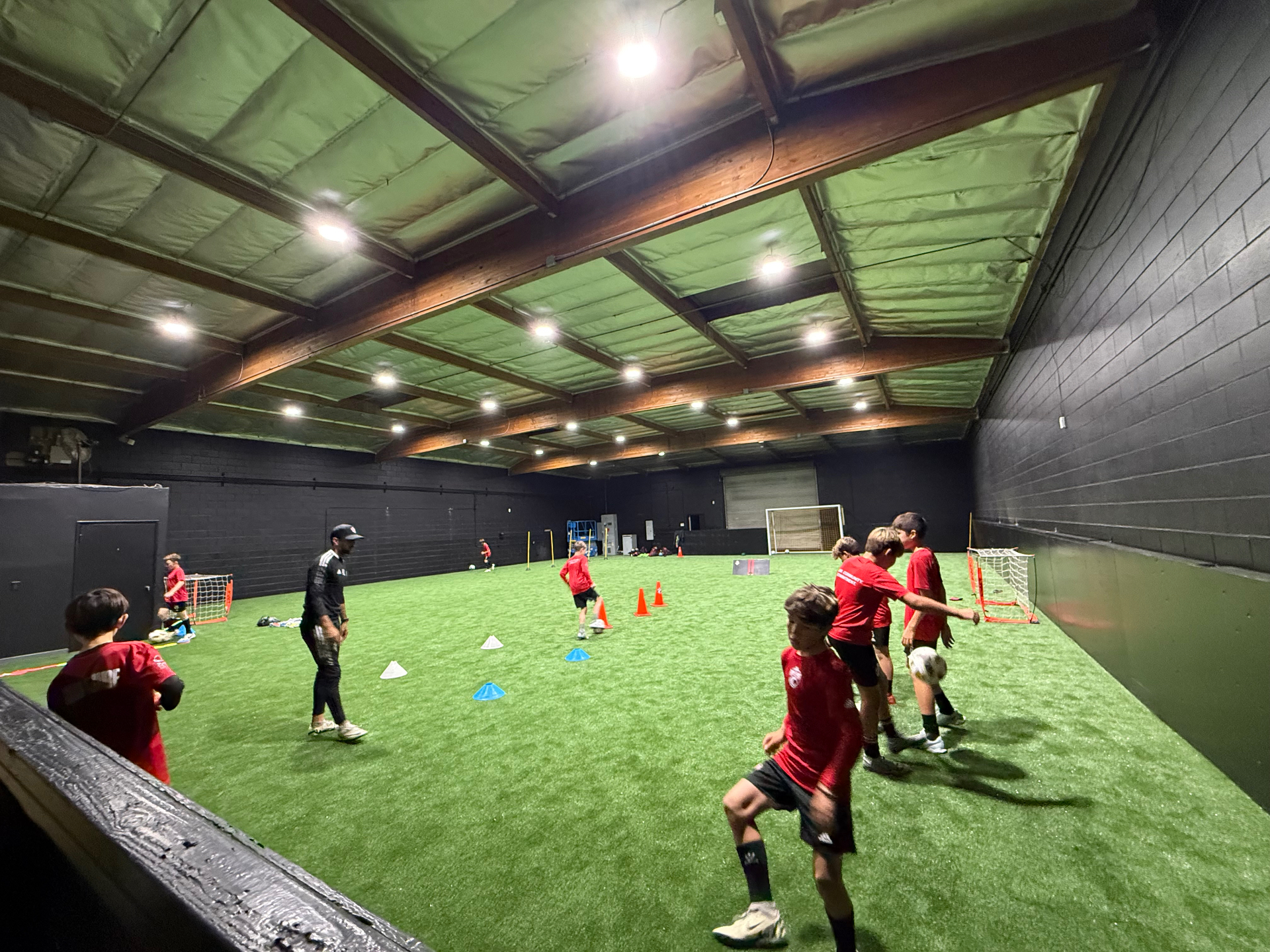 Wide view of the indoor field with players running drills